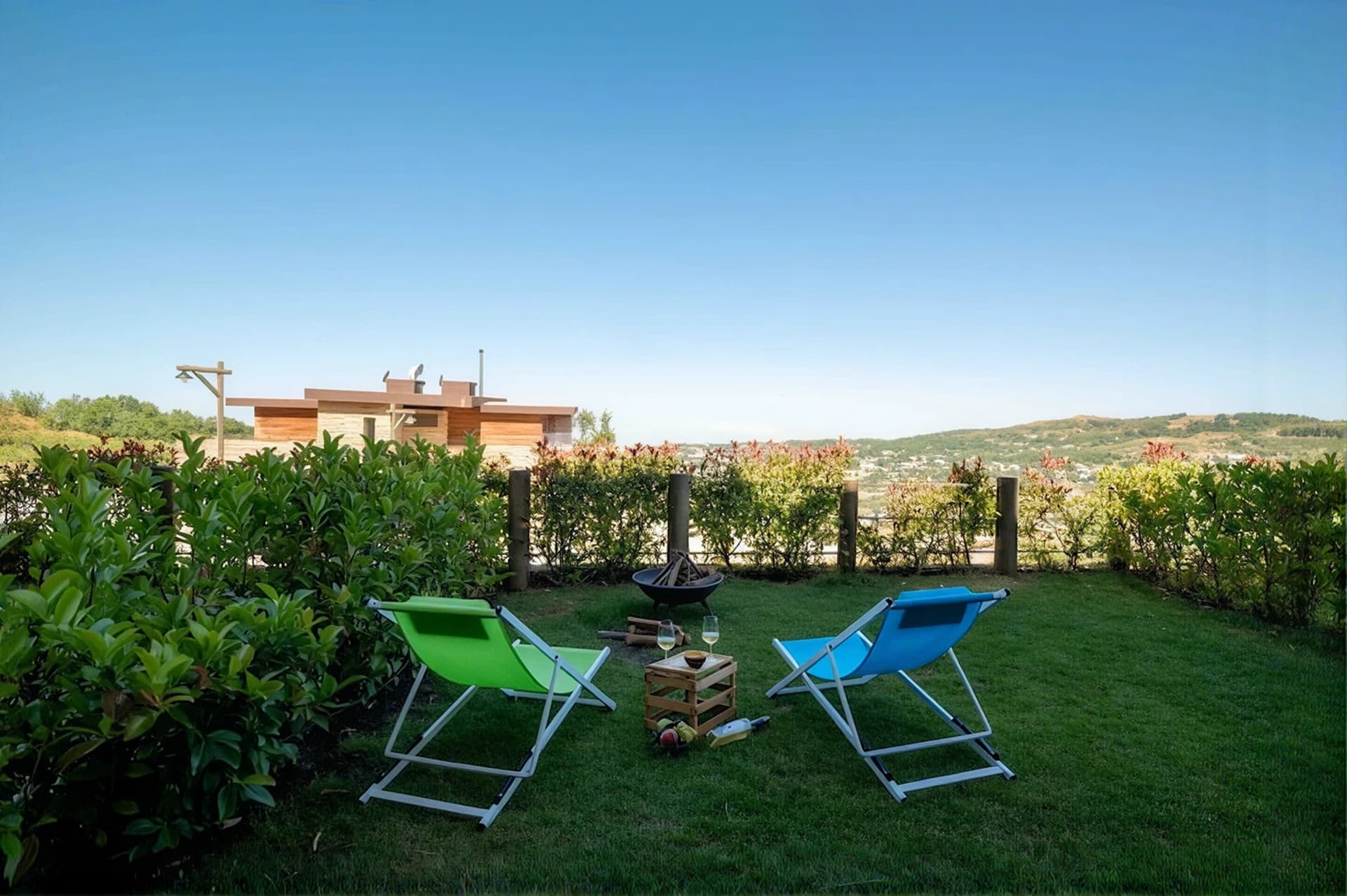 Lounge chairs and the fire pit on the lawn at The Nest, mountains beyond