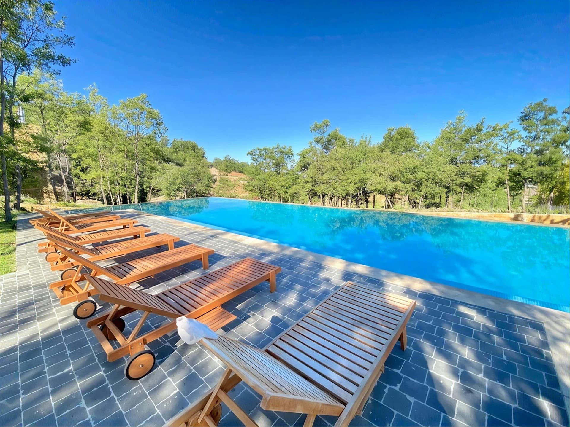 Shared seasonal infinity pool lined with sun loungers