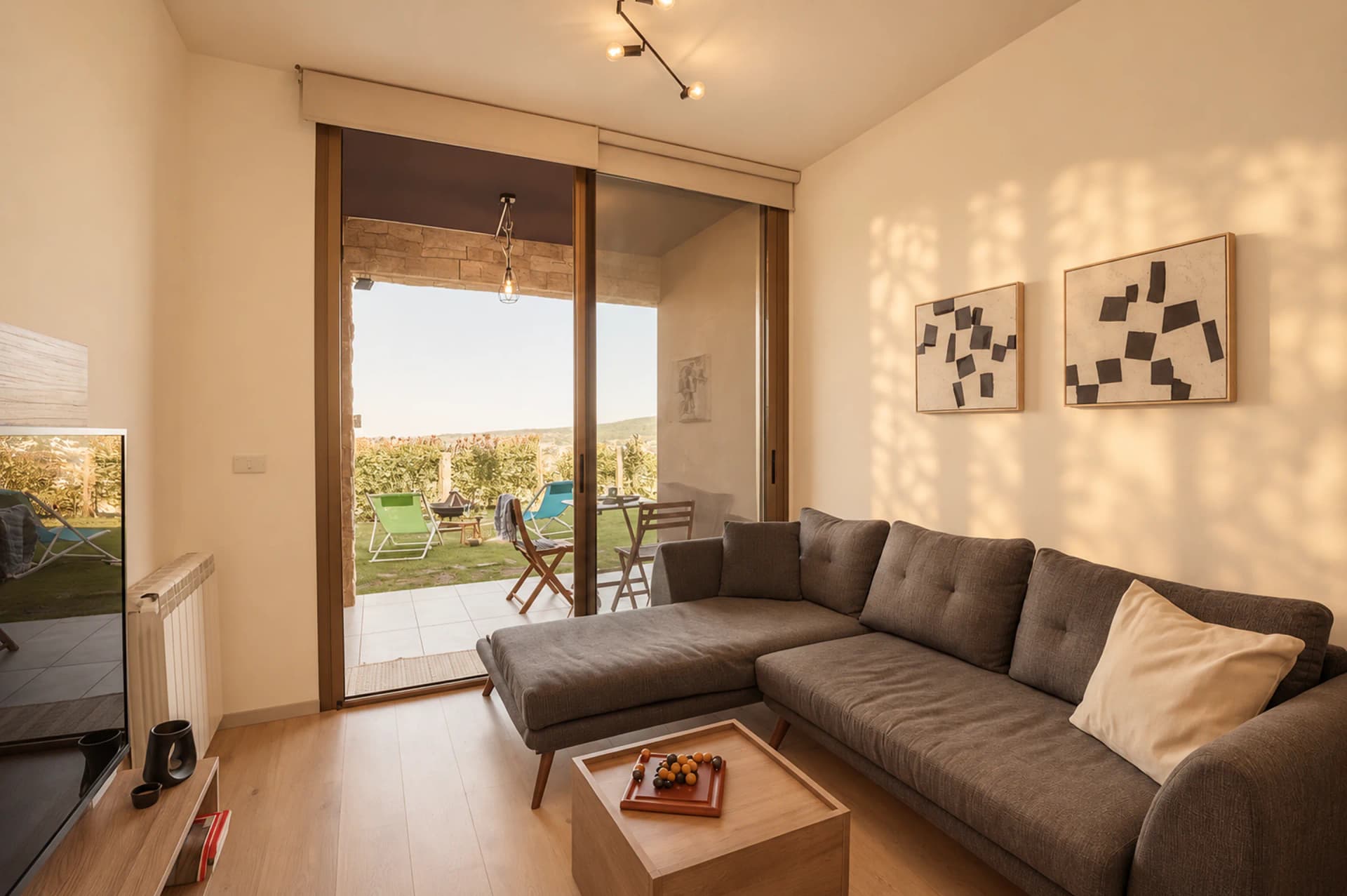 The sunlit living room of The Nest, the glass doors open onto the private garden
