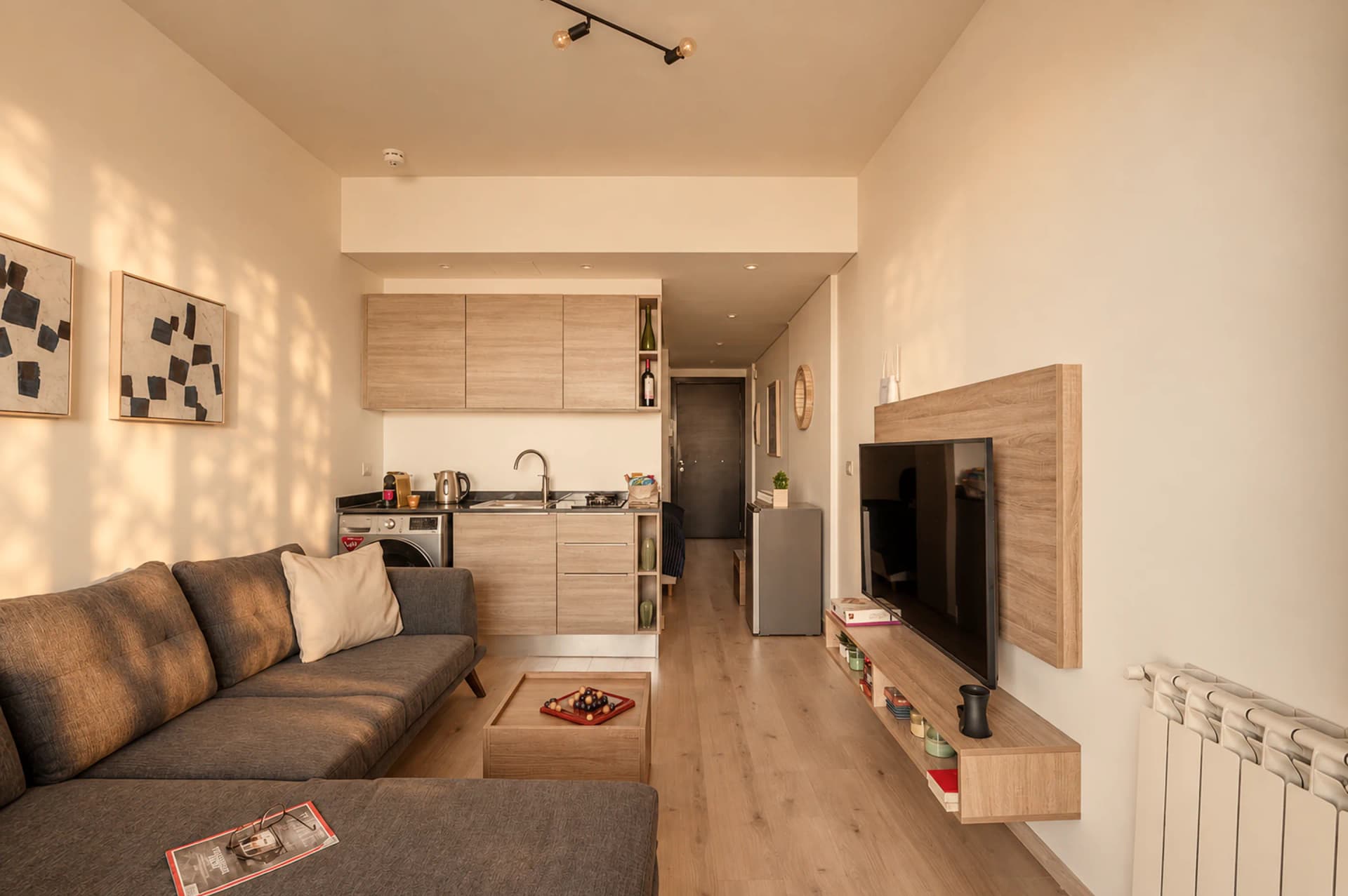 The sunlit open-plan living room you walk into, the kitchenette and the hallway beyond
