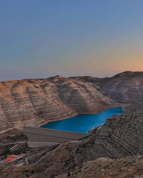 The Chabrouh dam wall and its blue reservoir among the terraced hills at dusk