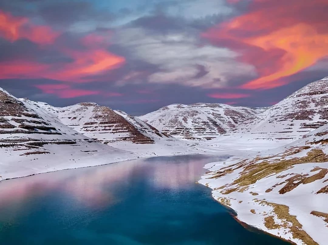 Chabrouh reservoir in winter, snow on the terraced hills under a pink sunset sky