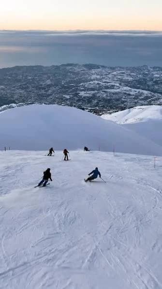 Skiers on a Mzaar slope, the clouds and the coast far below
